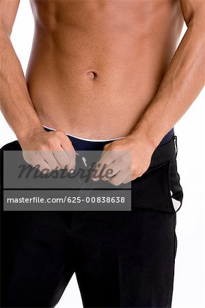 Mid section view of a man buttoning his pants