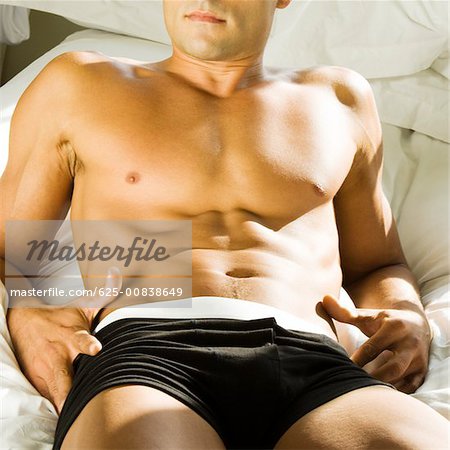 Mid section view of a young man lying on the bed