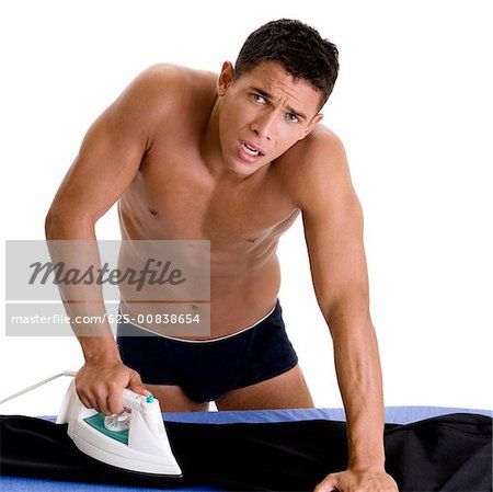 Portrait of a young man ironing his pants