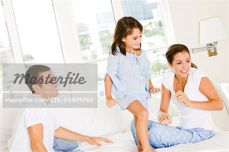 Parents and their daughter sitting on the bed