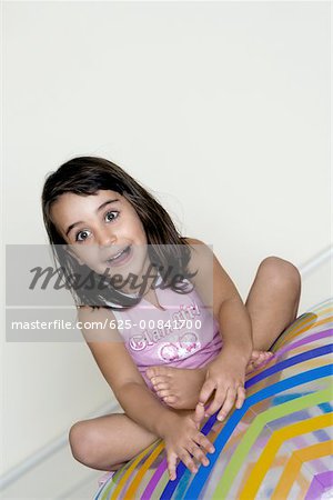 Gros plan d'une jeune fille assise sur une grosse boule gonflable