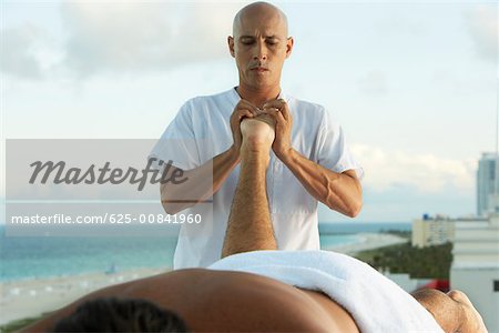 Close-up of a massage therapist giving a young man a foot massage