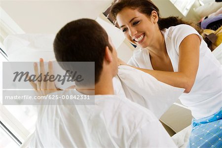 Gros plan d'un jeune couple ayant une bataille d'oreillers