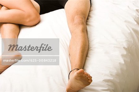 Low section view of a young couple lying on the bed