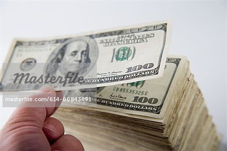 Person stacking hundred dollar bills