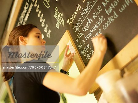 Woman Writing Menu on Restaurant Chalkboard