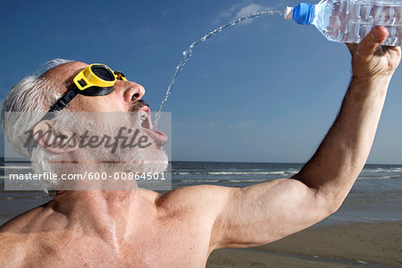 Man on Beach Drinking from Water Bottle