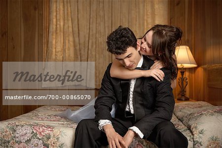 Young Couple in Formal Wear on Bed in Motel Room