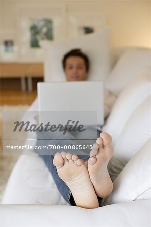 Mann mit Laptop auf Sofa