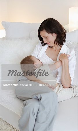 Frau Breastfeeding Baby auf Sofa