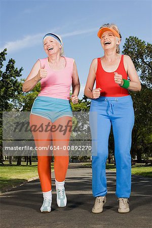 Two mature adult women running in park