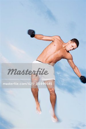 Low angle view of a young man jumping with his arms outstretched