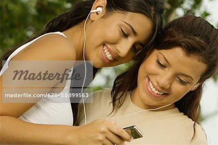 Close-up of two teenage girls holding an MP3 player listening to music