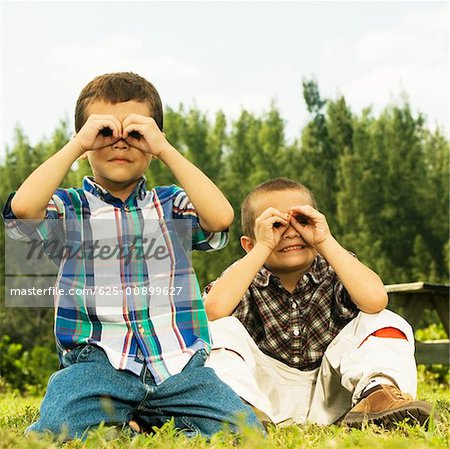 Close-up of two boys looking through their hands