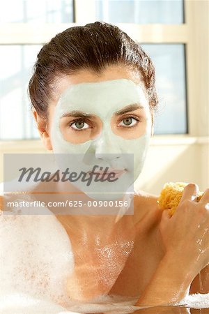 Portrait of a young woman scrubbing herself with a sponge
