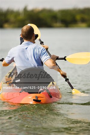 Vue arrière d'un jeune homme en kayak dans un lac