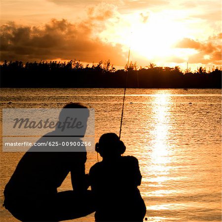 Silhouette of a father and his son fishing