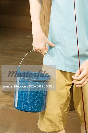 Mid section view of a man holding a fishing rod and a bucket