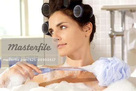 Gros plan d'une jeune femme, frottant son épaule avec une éponge de bain