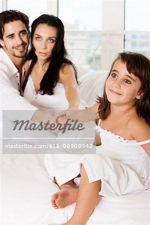 Close-up of a young couple holding their daughter's hands