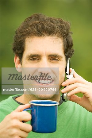 Portrait d'un homme adult moyen parler sur un téléphone mobile tenant une tasse de café