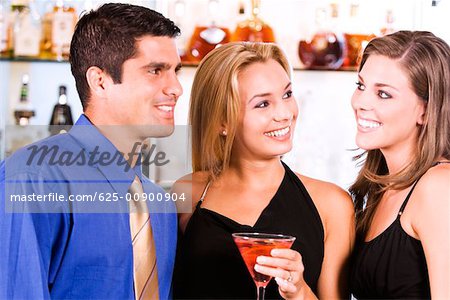 Close-up of two young women and a mid adult man in a bar