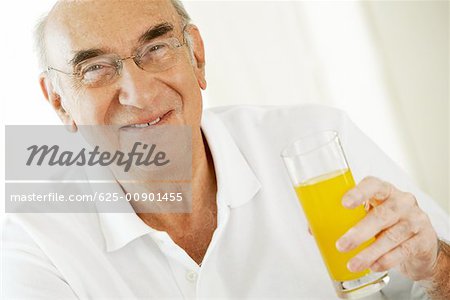 Portrait d'un homme senior tenant un verre de jus