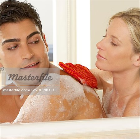 Close-up of a young woman scrubbing a young man's back