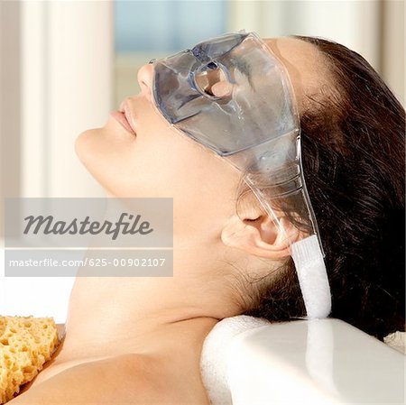 Close-up of a young woman wearing an eye mask in a bathtub
