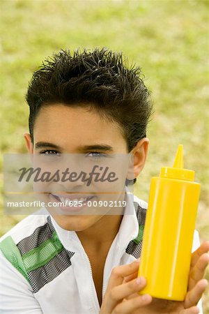 Portrait d'un garçon tenant une bouteille de sauce