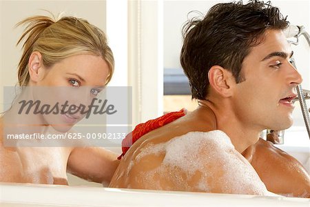 Portrait of a young woman scrubbing a young man's back