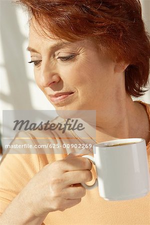 Gros plan d'une femme senior tenant une tasse de café