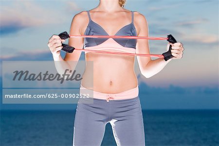 Mid section view of a young woman exercising with a resistance band