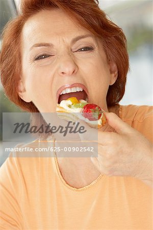 Portrait of a senior woman eating a fruit tart