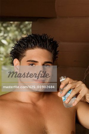 Portrait of a bare chested young man holding a water bottle