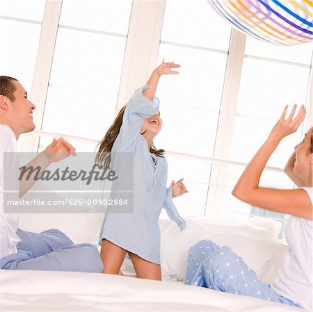 Parents playing with their daughter on the bed