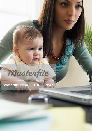Mutter mit Laptopcomputer mit Baby auf dem Schoß