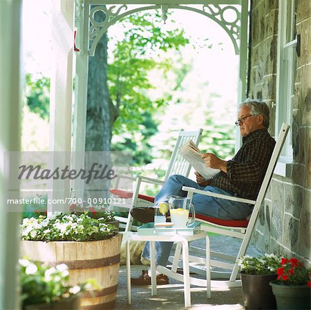 Homme lisant le journal sur le porche de l'avant