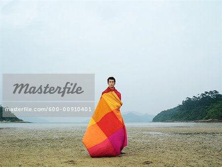 Man Wrapped in Blanket, Standing on Beach