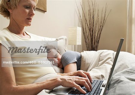 Couple avec ordinateur portable dans le lit