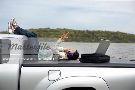 Femme assise l'arrière du camion à l'aide de téléphone portable