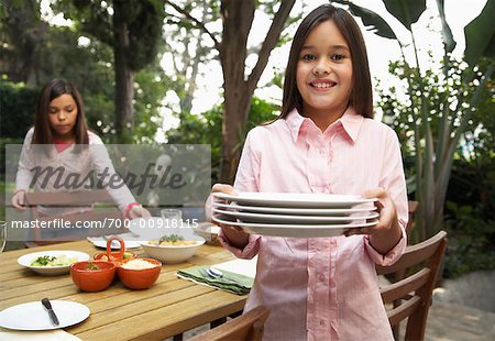 Two Girls Setting Table For Dinner Outdoors