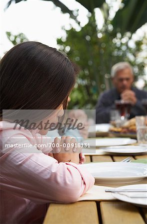 Fille avec famille disant Grace avant le dîner en plein air