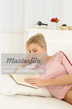 Femme allongée sur un lit, un livre de lecture