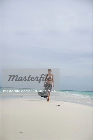 Young girl wearing bikini and pareo, walking along the beach