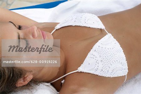 Young girl wearing bikini, lying on towel, sleeping