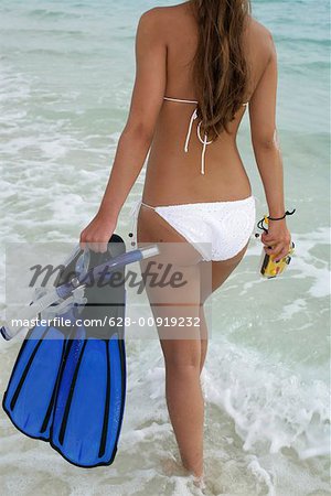 Jeune fille marche avec équipement de snorkeling et sous la caméra de l'eau le long de la plage