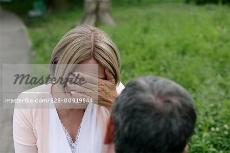 Mature woman covering her eyes in front of man