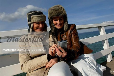 Deux femmes matures portant des fourrures chapeaux et tableaux à la recherche d'un appareil photo numérique