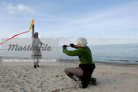Zwei Reife Frauen fliegen einen Drachen am Ostsee-Strand